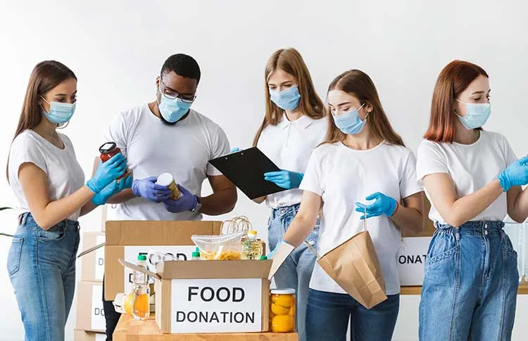 Volunteers in gloves sorting and logging donated food into cartons